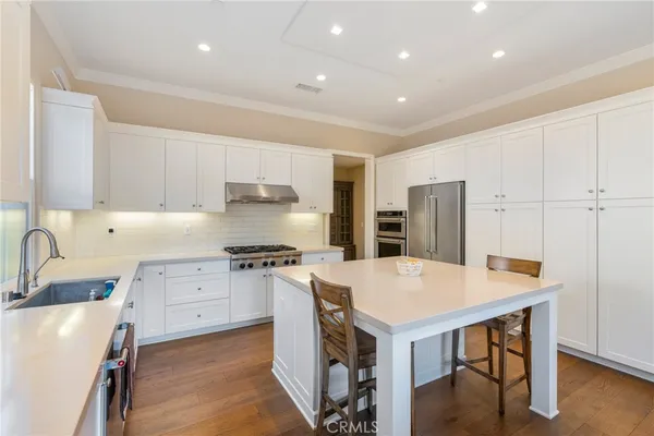 a kitchen with a stove a refrigerator and a sink with wooden floor