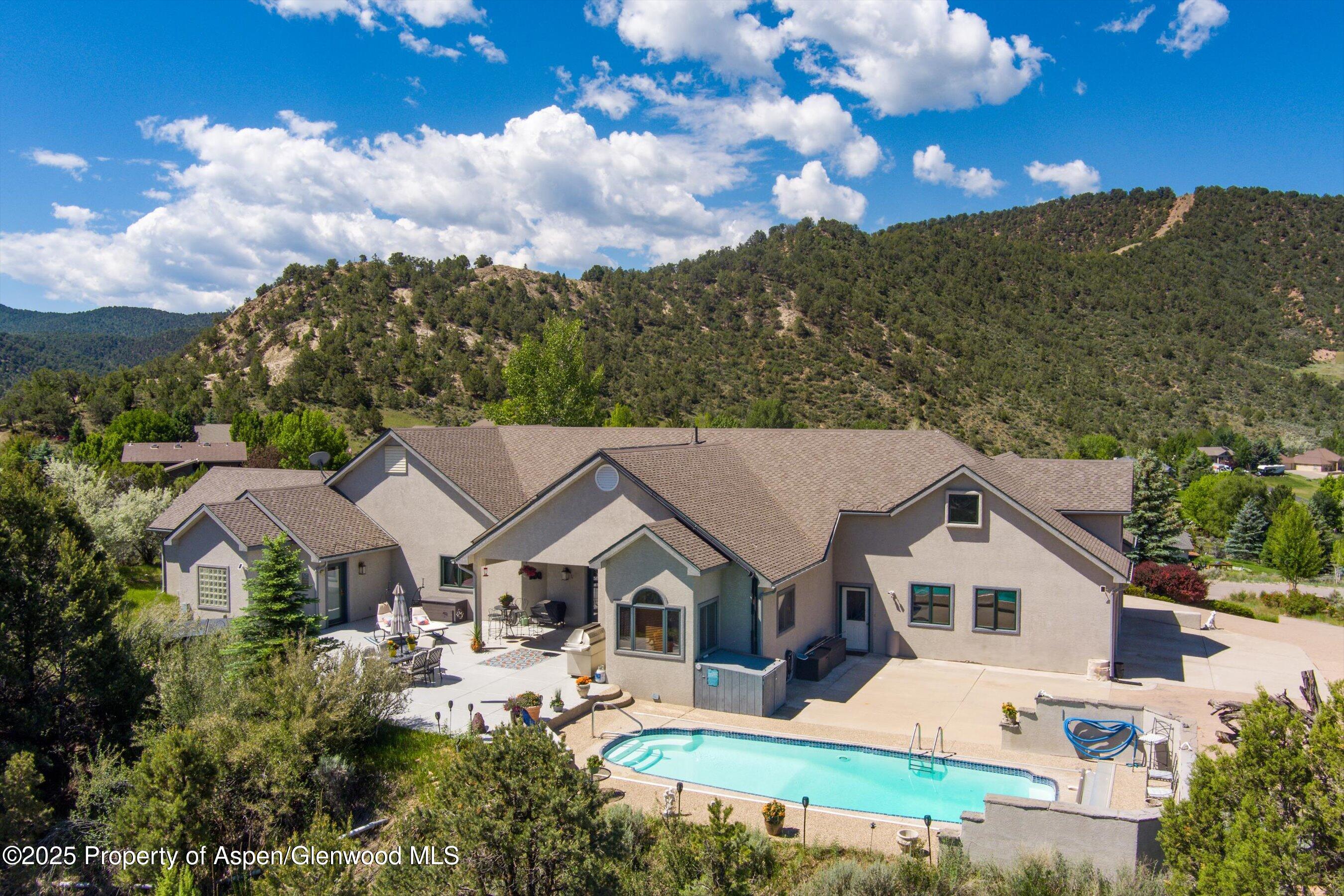 an aerial view of a house with swimming pool and trees