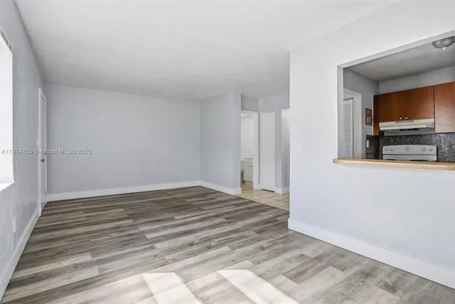 a view of a livingroom with wooden floor and a kitchen space