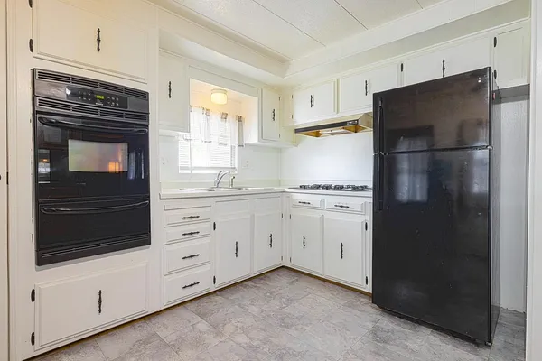 a kitchen with granite countertop white cabinets and stainless steel appliances