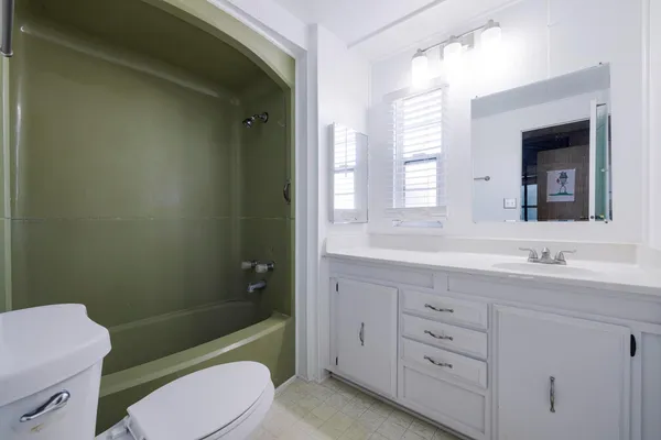 a bathroom with a sink a toilet a mirror a vanity and window