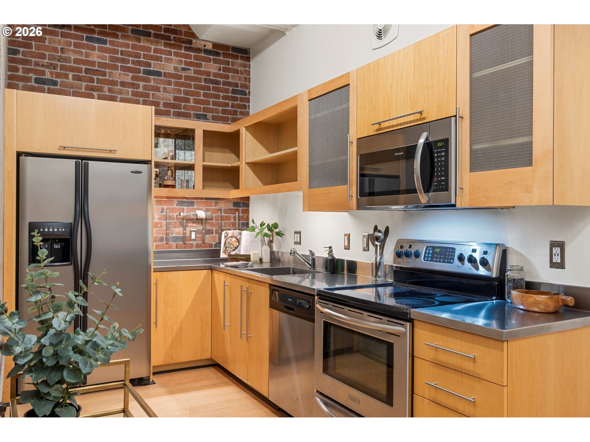 1400 Northwest Irving Street, Unit 322 Portland, OR 97209 - Photo 6 of 27 a kitchen with stainless steel appliances granite countertop a refrigerator a sink a stove a microwave and wooden cabinets
