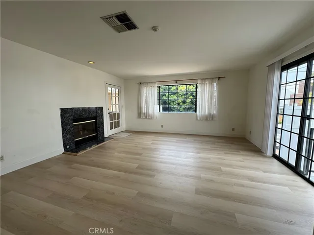 an empty room with windows and fireplace