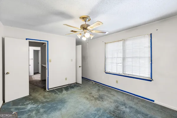 an empty room with windows and fan