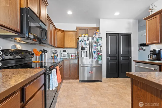 a kitchen with stainless steel appliances granite countertop a refrigerator a stove and a sink
