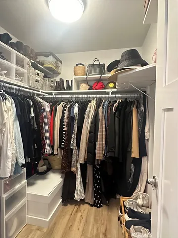 a view of walk in closet with clothes and shoes