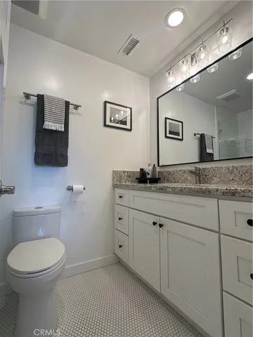 a bathroom with a granite countertop toilet sink and mirror