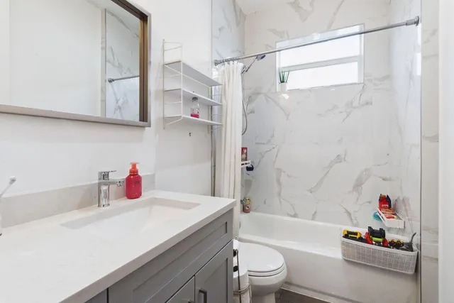 a bathroom with a granite countertop sink a toilet and shower