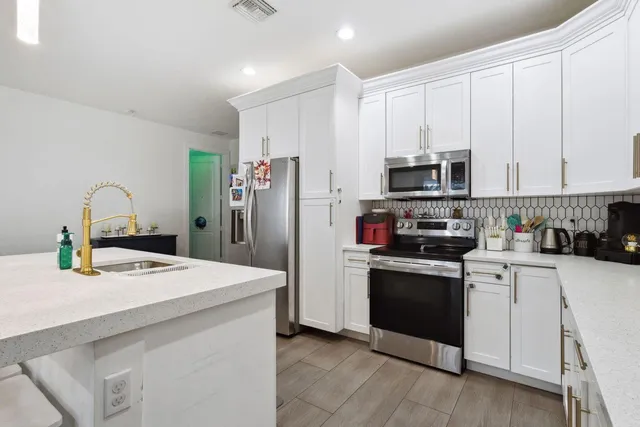 a kitchen with stainless steel appliances kitchen island a sink refrigerator and cabinets