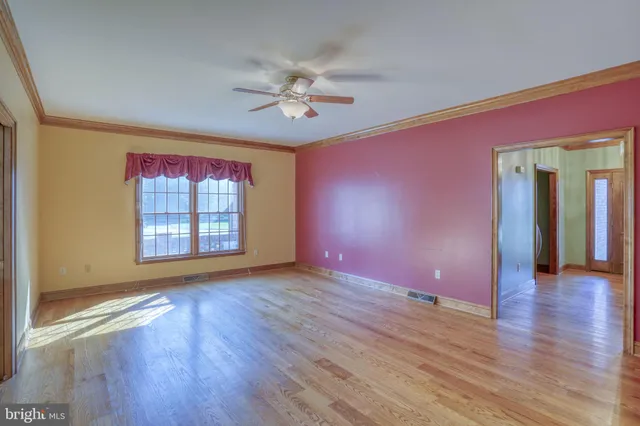 a view of empty room with wooden floor and fan