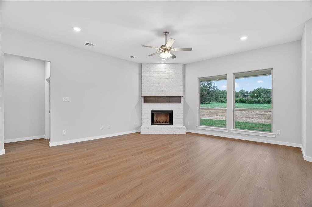 321 Skeen Peak Springtown, TX 76082 - Photo 14 of 37 Living area featuring a corner white-painted brick fireplace with a wood mantel, wood-finish flooring, recessed lighting, and a ceiling fan
