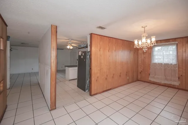 a view of a hallway with chandelier and a refrigerator