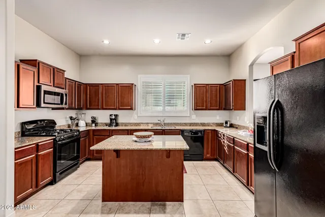 a kitchen with stainless steel appliances granite countertop a stove top oven a sink a refrigerator and dishwasher