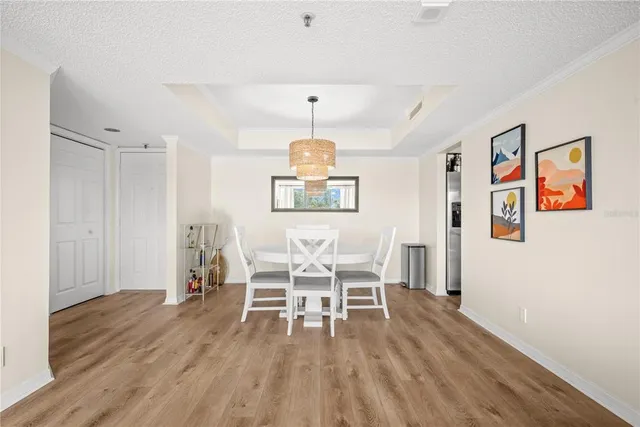 a dining room with wooden floor a chandelier a wooden table and chairs