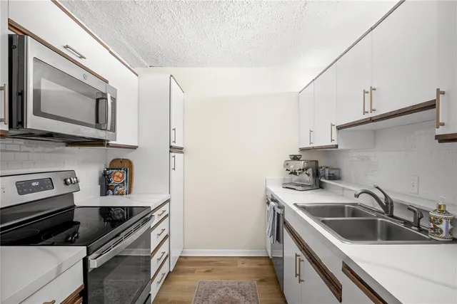 a kitchen with stainless steel appliances a sink a stove a microwave and cabinets