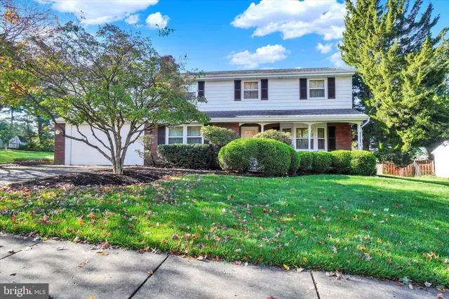 a front view of a house with a yard and tree s