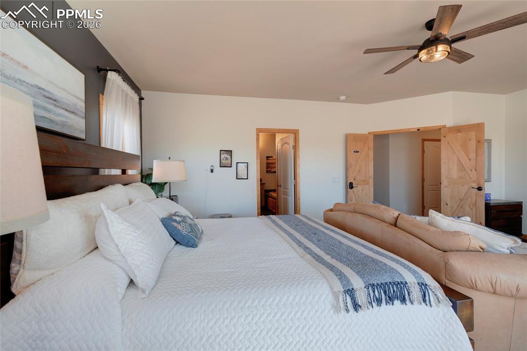 24965 Cave Spg Trail Elbert, CO 80106 - Photo 14 of 50 a bedroom with a bed a couch and a ceiling fan