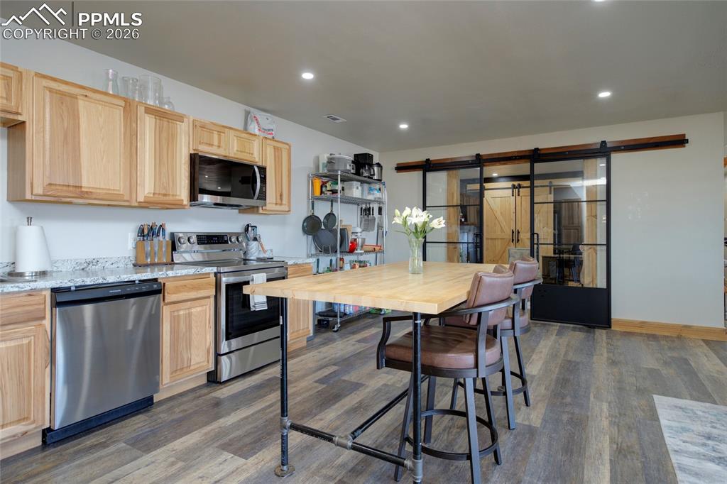 24965 Cave Spg Trail Elbert, CO 80106 - Photo 6 of 50 a kitchen with stainless steel appliances granite countertop a stove a sink a microwave a dining table and chairs with wooden floor