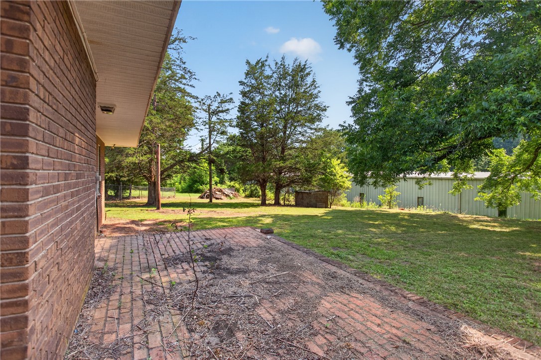 1412 Simpson Road Pendleton, SC 29670 - Photo 47 of 48 A classic brick structure with a paver patio extends into a spacious, well-maintained lawn.