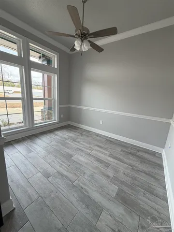 an empty room with wooden floor fan and windows