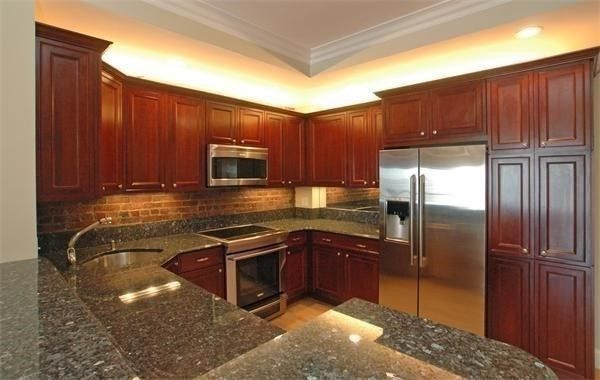 a kitchen with stainless steel appliances granite countertop a refrigerator a stove and a sink with wooden cabinets