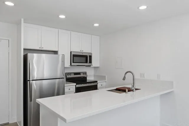 a kitchen with stainless steel appliances a refrigerator a sink a stove a microwave and cabinets