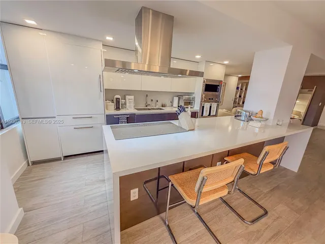 a kitchen with stainless steel appliances a refrigerator a sink dishwasher with a dining table and chairs