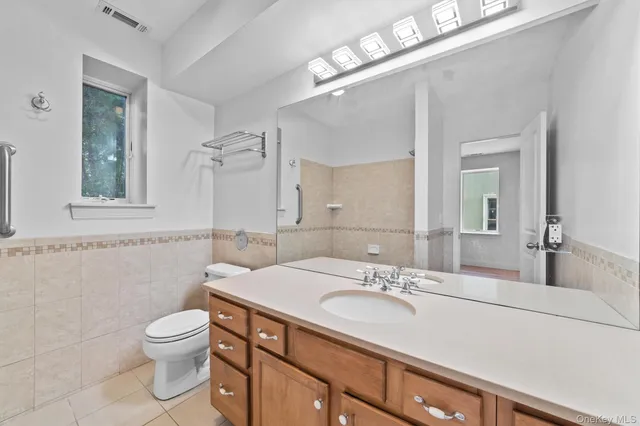 a bathroom with a granite countertop sink a toilet a mirror and shower