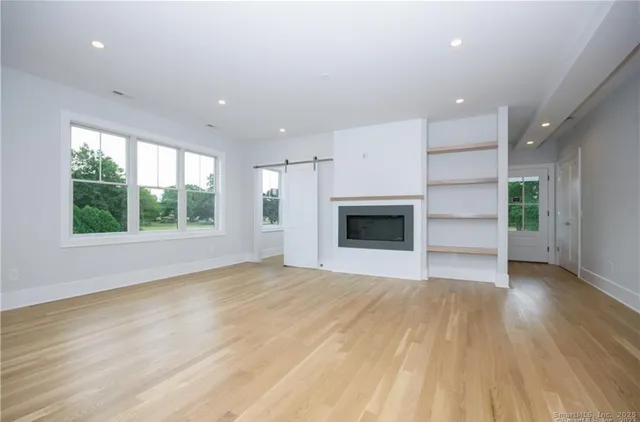 an empty room with wooden floor a fireplace and windows