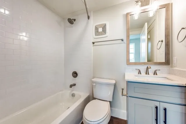 a bathroom with a toilet sink vanity tub and shower