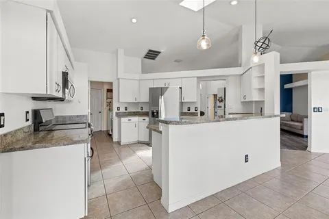 a kitchen with kitchen island granite countertop a sink a counter top space and cabinets