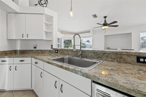 a kitchen with granite countertop a sink a counter top space cabinets and stainless steel appliances