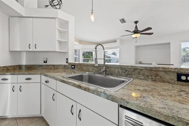 a kitchen with granite countertop a sink a counter top space cabinets and stainless steel appliances
