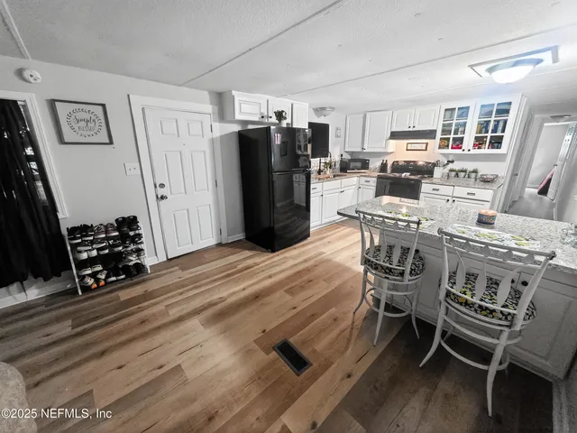 a kitchen with stainless steel appliances a refrigerator a stove a dining table and chairs with wooden floor