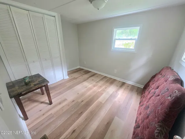 a view of a bedroom with wooden floor and a ceiling fan