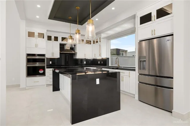 a kitchen with stainless steel appliances granite countertop a refrigerator a stove a sink and a microwave