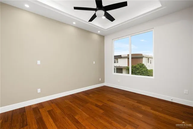 a view of empty room with wooden floor and fan