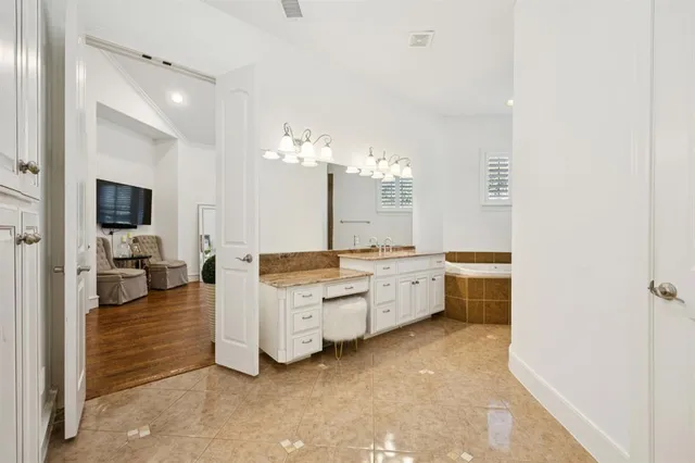 a large white kitchen with a sink and dishwasher a fireplace with wooden floor