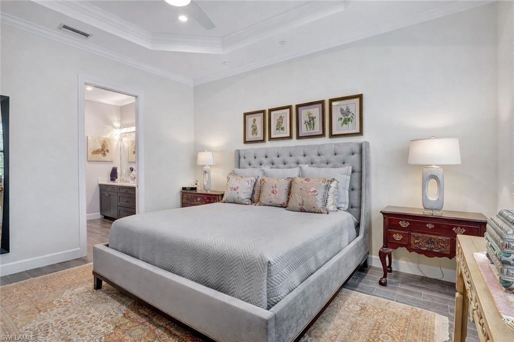 9637 Montelanico Loop, Unit 203 Naples, FL 34119 - Photo 20 of 50 Primary Bedroom with porcelain wood-like floors, a ceiling fan, crown molding, a raised ceiling, and primary bathroom