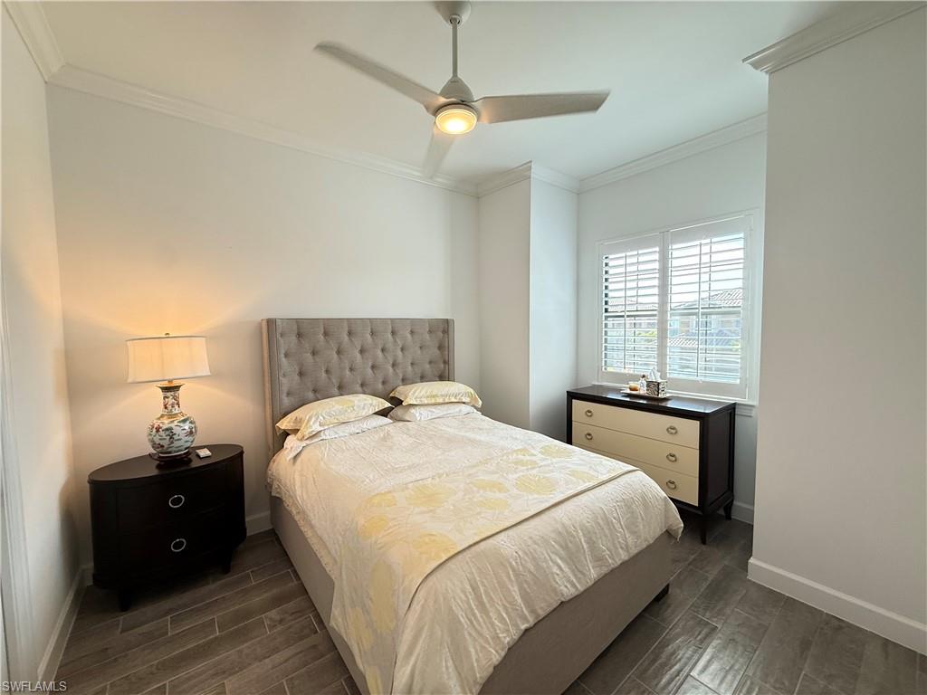 9637 Montelanico Loop, Unit 203 Naples, FL 34119 - Photo 25 of 50 Bedroom with crown molding, porcelain wood-like flooring, plantation shutters, ceiling fan seen, and adjacent bathroom with full bathnot pictured