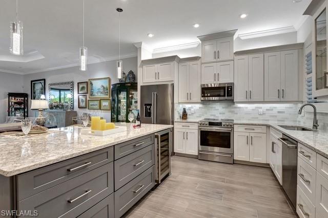 9637 Montelanico Loop, Unit 203 Naples, FL 34119 - Photo 5 of 50 featuring wine cooler, decorative backsplash, Cambria Quartz counters, upgraded stainless steel appliances, lower sized gray cabs with additional storage and pull outs