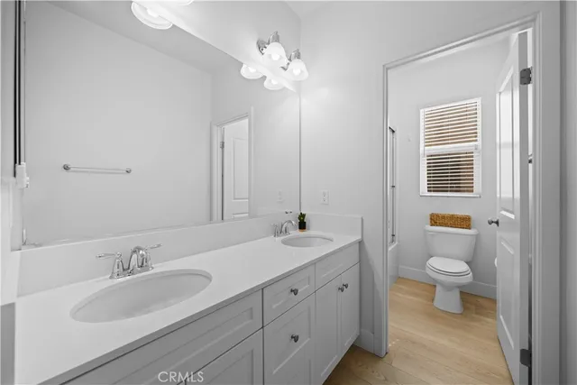 a bathroom with a double vanity sink a toilet and a window