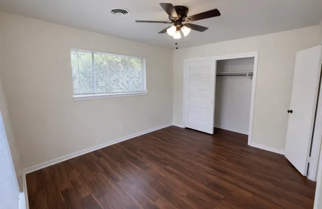 a view of empty room with wooden floor and ceiling fan