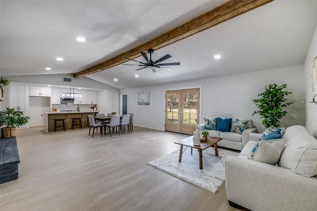 a living room with furniture and potted plants with wooden floor