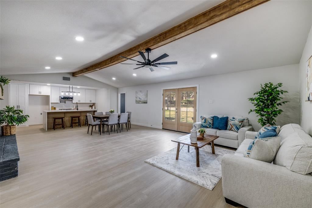 a living room with furniture and potted plants with wooden floor