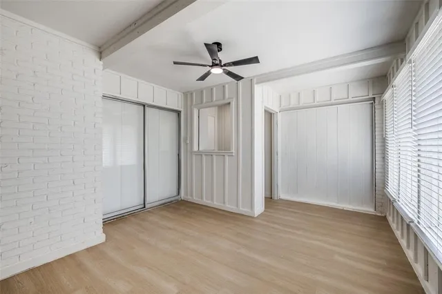 an empty room with wooden floor fan and windows