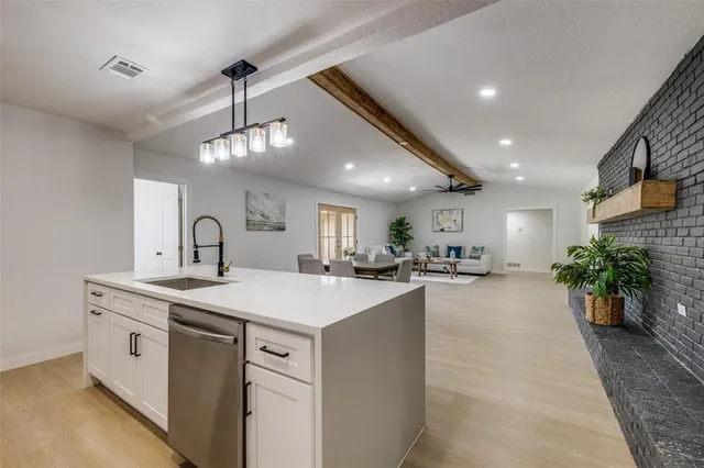 a large kitchen with sink a counter top space and living room view