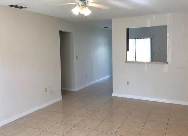 an empty room with windows and fan