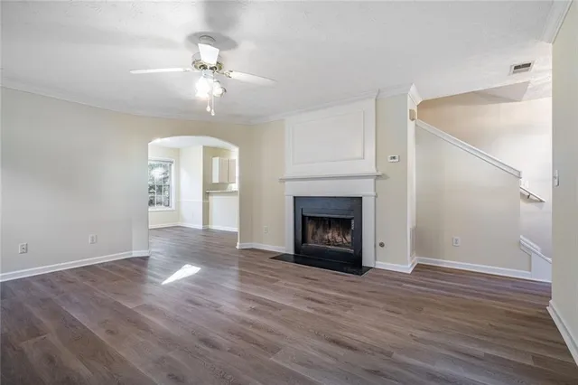 a view of an empty room with wooden floor fireplace and a window