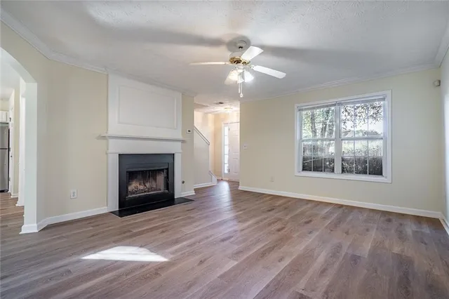 a view of an empty room with wooden floor a fireplace and a window